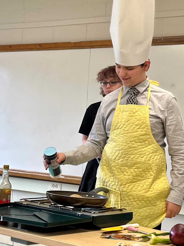 A student in Mandarin class demonstrates how to make an authentic Chinese dish.