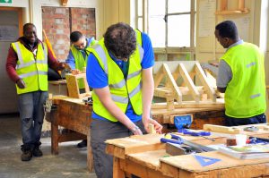 Group of individuals in a workshop practicing woodworking