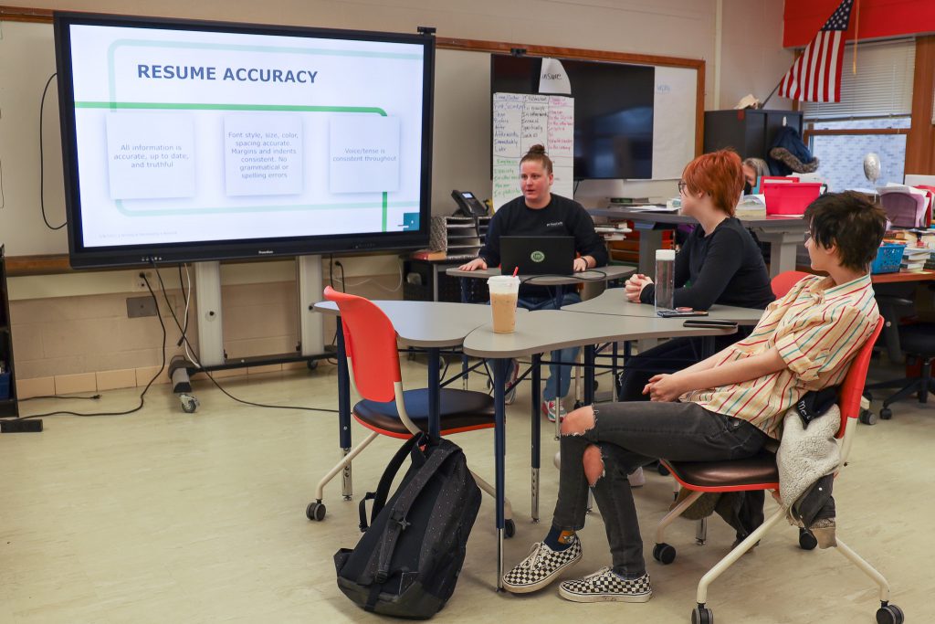 Students sit in a classroom and listen to a presenter talk about writing and developing a resume.