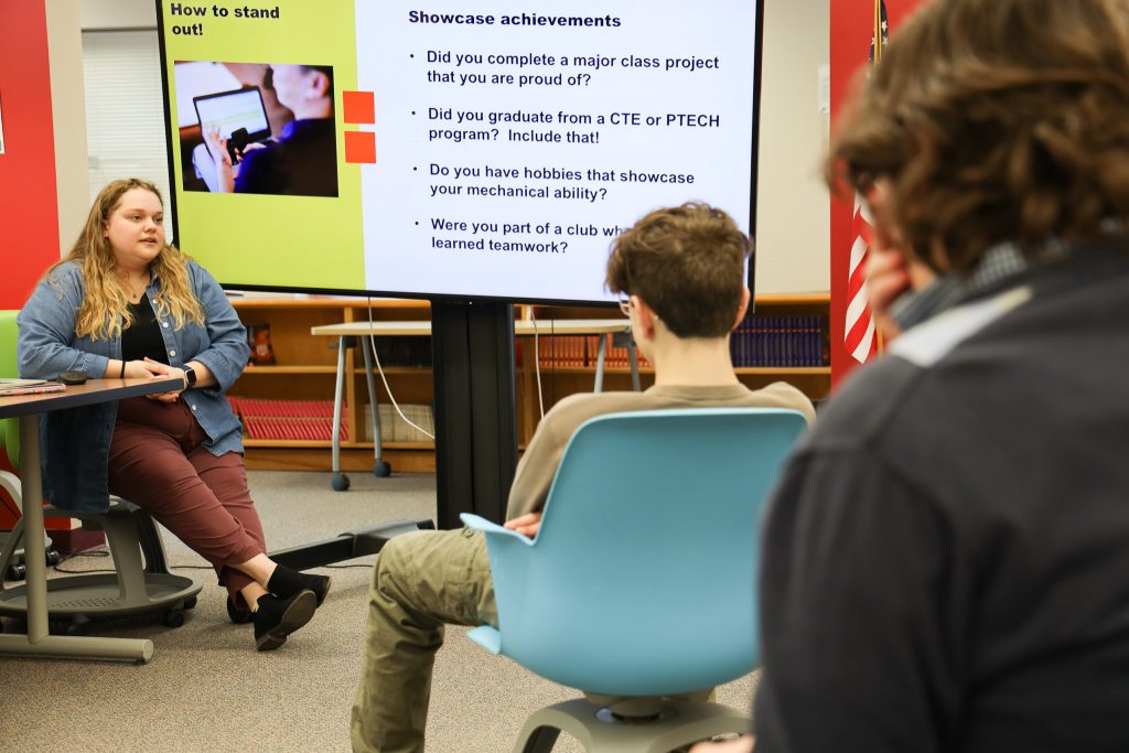 Students sit in a classroom and listen to a presenter talk about writing and developing a resume.