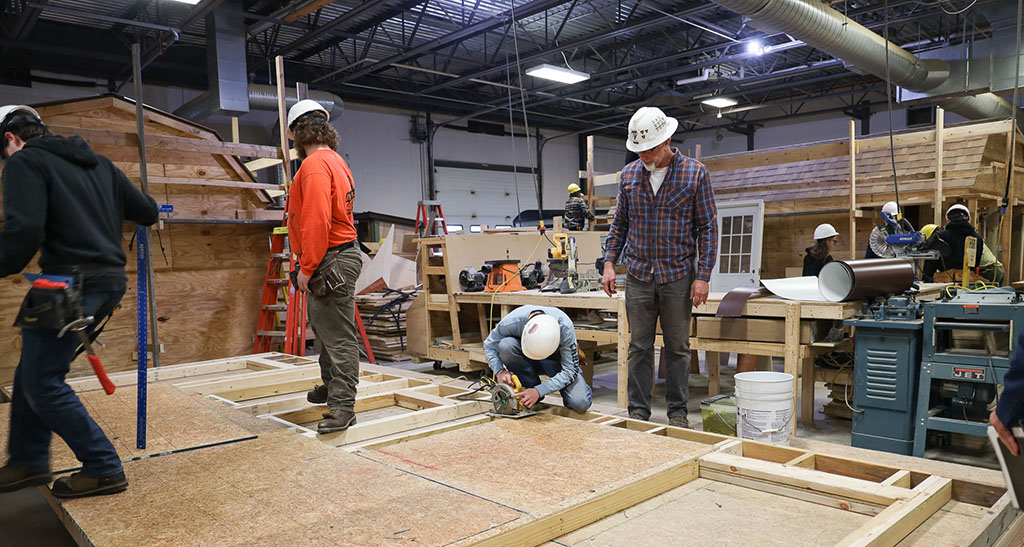 A student uses a circular saw while the instructor looks on. 
