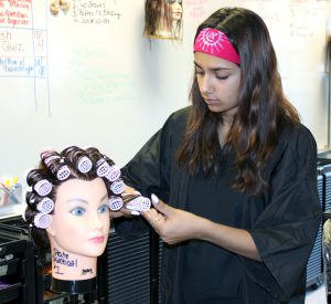 A student adds rollers to a mannequin head