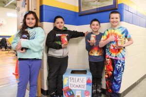 A group of students each hold a non-perishable food item that will be donated to a local food pantry.
