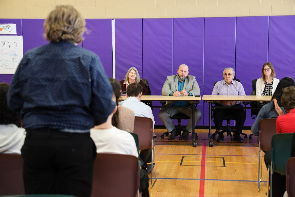 A students directs a question to a panel of local business professionals.