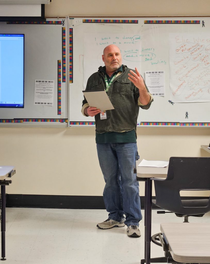 Adirondack Academy teacher Tom Halloran speaks to a group of PTECH students about poetry.