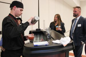 A Culinary Arts student pours a 'mocktail' while Greater Johnstown School District Superintendent Bill Crankshaw looks on. In the background is Johnstown Assistant Superintendent Alicia Koster.