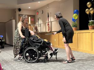 A teacher hands a certificate of completion to a student during a commencement ceremony.