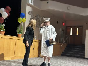 A student speaks with a teacher during a commencement ceremony.