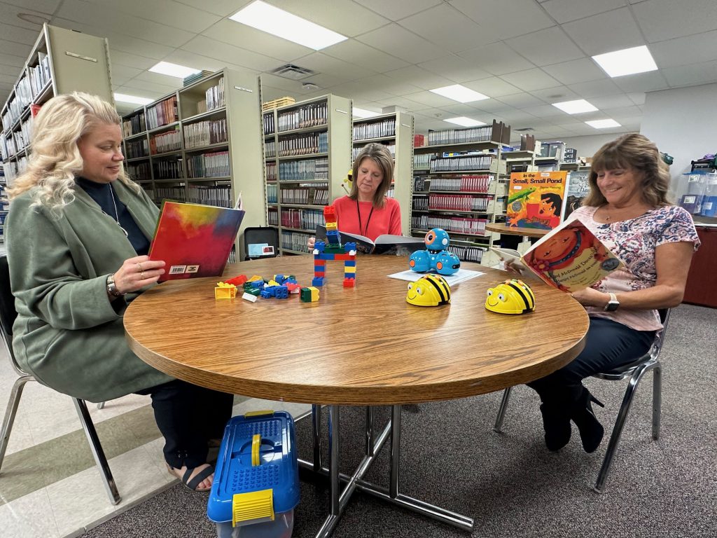 Members of the HFM Instructional Resource Center are pictured seated around a table each reading a different book